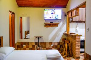 um quarto com uma cama e uma televisão na parede em Pousada Muro de Pedra em São Thomé das Letras