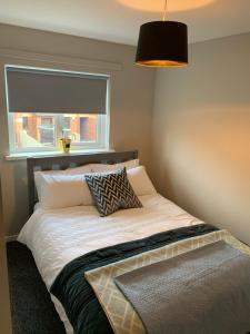 1 dormitorio con 1 cama con ventana y lámpara en Weekend City Break Plush Pad, en Belfast