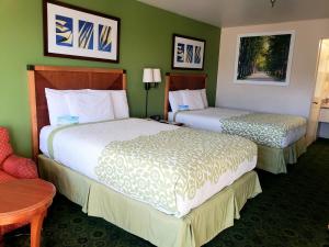 two beds in a hotel room with green walls at Days Inn by Wyndham Westley in Westley