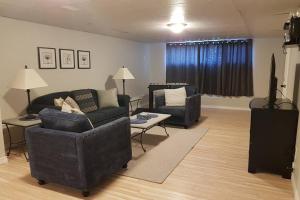 uma sala de estar com um sofá e uma cadeira em Sarnia Central Six - BIG 6 BR 2 BA - patio and BBQ em Sarnia