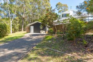 a driveway leading to a white house with trees at Gorgeous Beachside Cottage Jervis Bay in Vincentia