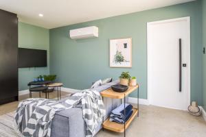 ein Wohnzimmer mit grünen Wänden und einem Sofa in der Unterkunft Gorgeous Beachside Cottage Jervis Bay in Vincentia