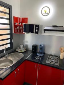 eine kleine Küche mit einer Spüle und einer Mikrowelle in der Unterkunft MALAKA F1 TOUT CONFORT Le Moule avec Piscine in Le Moule