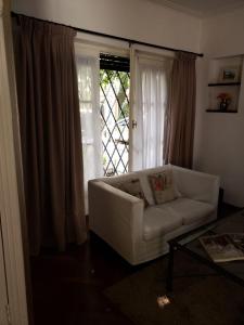 a living room with a white couch in front of a window at La Petite Maison San Isidro in San Isidro