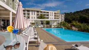 a hotel swimming pool with chairs and umbrellas at Best Western Plus Ajaccio Amirauté in Ajaccio