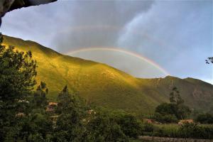 un arco iris en el cielo sobre una montaña en Illa Wasi Sacred Valley, en Urubamba