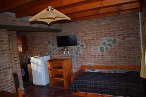 a bedroom with a brick wall with a bed and a tv at Cabañas La Rosada in Santa Rosa de Calamuchita