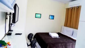 a hotel room with a bed and a television at Flat 02 in Jaguariaíva