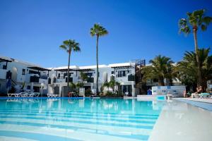 a large swimming pool with palm trees and buildings at Plaza Azul in Puerto del Carmen