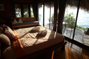 - une chambre avec un lit et une vue sur l'eau dans l'établissement wetlandcamp บ้านชายเล, à Phatthalung