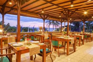 ein Restaurant mit Tischen und Stühlen und Blick auf das Meer in der Unterkunft Puri Bagus Candidasa in Candidasa