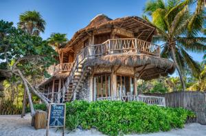 atropical hut with a sign in front of it at Alaya Tulum by Ahau Collection in Tulum