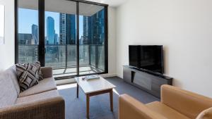 uma sala de estar com um sofá, uma televisão e uma mesa em WRAP on Southbank em Melbourne