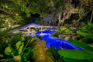 a swimming pool in a garden at night at Tambuli Seaside Resort and Spa in Mactan