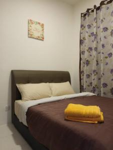 a bed with a yellow blanket on top of it at Rose Apartment Keafarm in Cameron Highlands