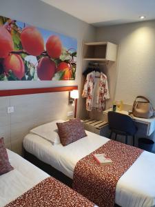 a hotel room with two beds and a desk at Hôtel Saint Louis in Le Thor