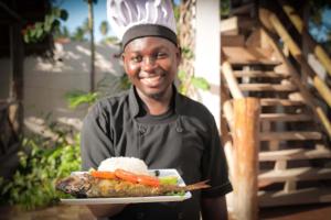 a man holding a plate of food with vegetables on it at Isla Bonita Zanzibar Beach Resort in Matemwe