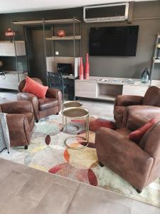 a living room with leather furniture and a flat screen tv at Hôtel Saint Louis in Le Thor