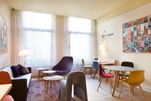 ein Wohnzimmer mit Tischen, Stühlen und einem Sofa in der Unterkunft Hotel The Neighbour's Magnolia in Amsterdam