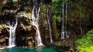 a group of waterfalls on the side of a mountain at Le Gecko Vert in Manapany-les Bains