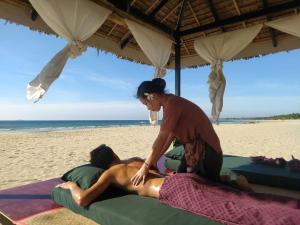 Una donna sulla spiaggia con una donna sdraiata su un asciugamano di Emerald Sea Resort a Ngwesaung