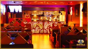 a restaurant with a bar with red and white at Hotel RAKS in Thanjāvūr