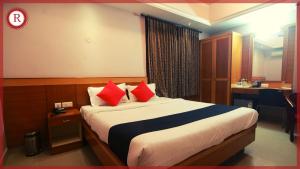 a bedroom with a large bed with red pillows at Hotel RAKS in Thanjāvūr +18 photos