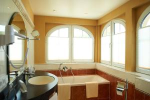 a bathroom with a tub and a sink and windows at Alte Landratsvilla Hotel Bender in Westerburg +19 photos