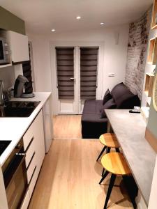 a kitchen and living room with a black couch in a room at Le cabanon in Méneslies