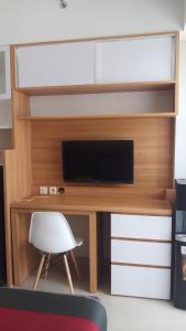 Un escritorio con un televisor y una silla blanca. en Ruby Apartment #1, en Yogyakarta