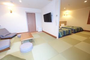 a hotel room with a bed and a tv at Station Hotel AU in Tsu