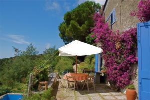 a table with an umbrella next to a building with purple flowers at Maison de Charme Giulietta in Bonassola