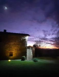 a stone building with a staircase in a yard at night at Podere Campovecchio in Rapale