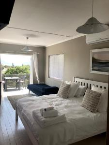 a bedroom with a large white bed and a balcony at Kommetjie Heaven in Kommetjie