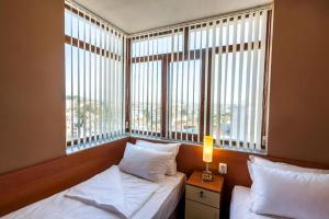 a bedroom with two beds and a large window at Panorama Top Floor Rooms in Hotel Tundzha in Yambol