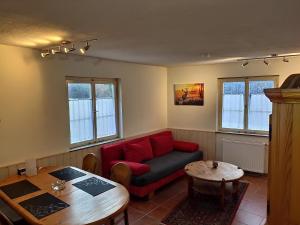 uma sala de estar com um sofá vermelho e uma mesa em Ferienhaus Schwarzwald Seewald Erzgrube Badesee 100% Natur em Seewald