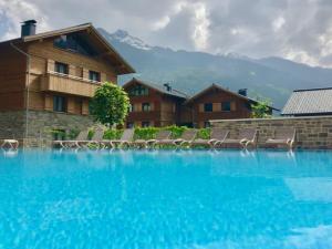 duży basen z krzesłami i budynek w obiekcie Grossglockner Alpin Lodge w mieście Matrei in Osttirol