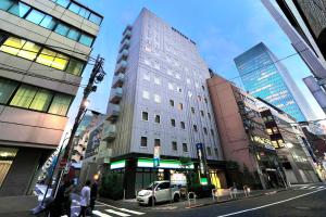 a tall white building on a city street with buildings at Meitetsu Inn Hamamatsucho in Tokyo