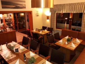 a restaurant with wooden tables and chairs in a room at Hotel das Möwenstübchen in Wremen