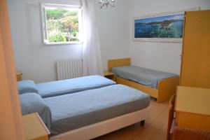 a small room with two beds and a window at Hotel Scoglio Bianco in Portoferraio