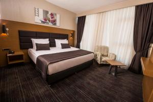 um quarto de hotel com uma cama e uma cadeira em New Garden Hotel em Diyarbakır