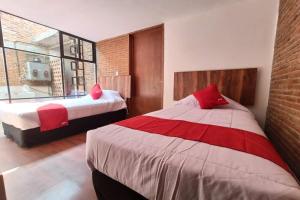 a bedroom with two beds with red pillows at Hotel de Guadalupe, Puebla in Puebla +28 photos