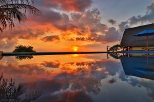 un reflet d'un coucher de soleil dans l'eau d'une piscine dans l'établissement Song Cang Bungalow, à Nusa Penida