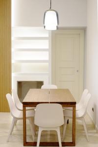 una sala da pranzo con tavolo in legno e sedie bianche di Domus Antonia a Castellammare di Stabia