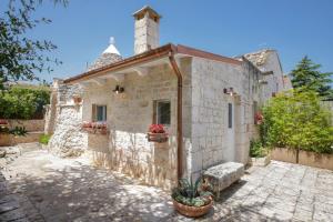 una piccola casa in pietra con camino e piante in vaso di Trulli&Dimore - Dimora di Genna a Castellana Grotte