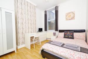 a white bedroom with a bed and a desk at Ceres Lodge in Plumstead