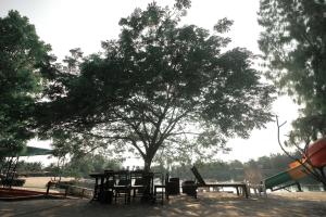 una mesa de picnic bajo un árbol junto a un parque infantil en Tara Beach Resort Udonthani, en Udon Thani