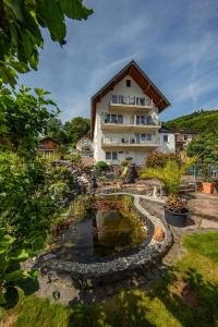 une maison avec un étang en face de celle-ci dans l'établissement Ferienweingut Klaus Thiesen Gästezimmer und Apartments, à Ellenz-Poltersdorf