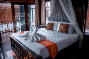 a bedroom with a canopy bed with white sheets and pillows at Tara Beach Resort Udonthani in Udon Thani