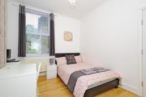 a white bedroom with a bed and a desk at Ceres Lodge in Plumstead